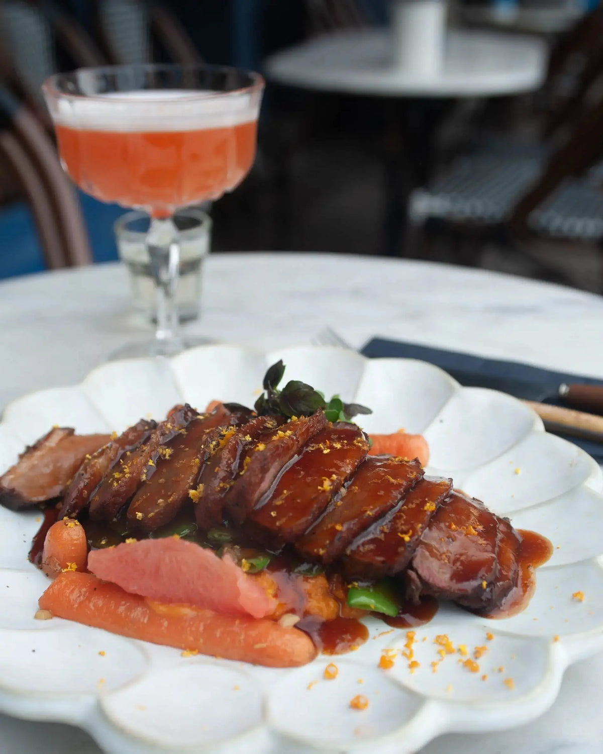 Plated food and a cocktail photographed on a restaurant table
