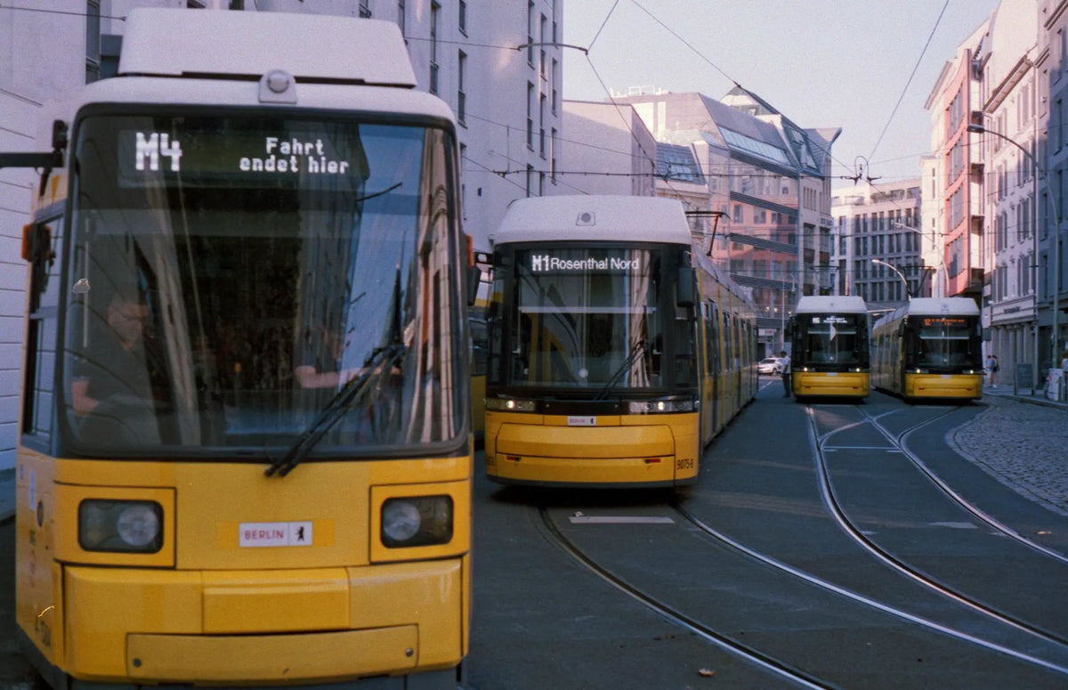 Yellow trams stand side by side on tracks between city buildings.