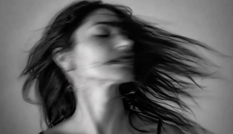 Black-and-white portrait of a woman with closed eyes and hair sweeping to one side.