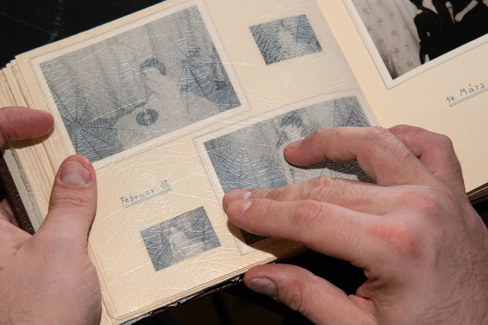 Hands carefully organising old family negatives in protective album sleeves