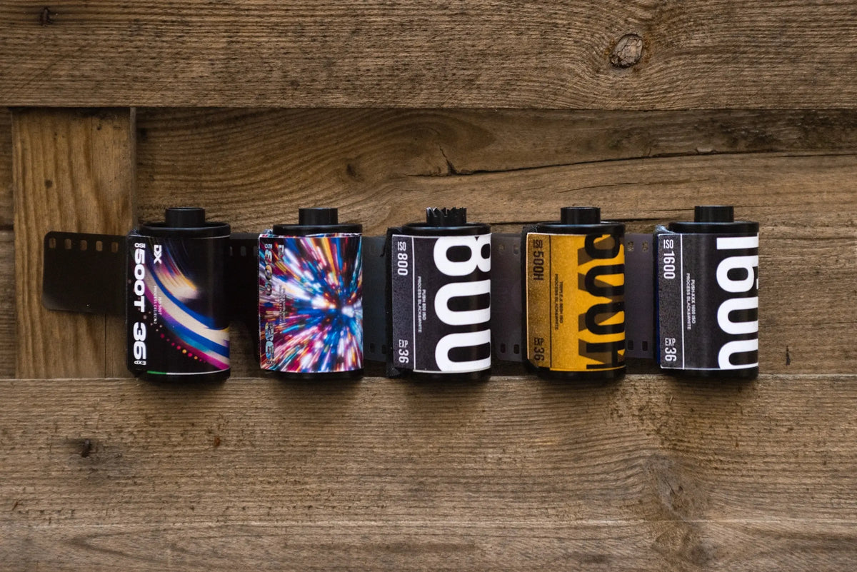 Film rolls with different ISO ratings arranged on a wooden surface