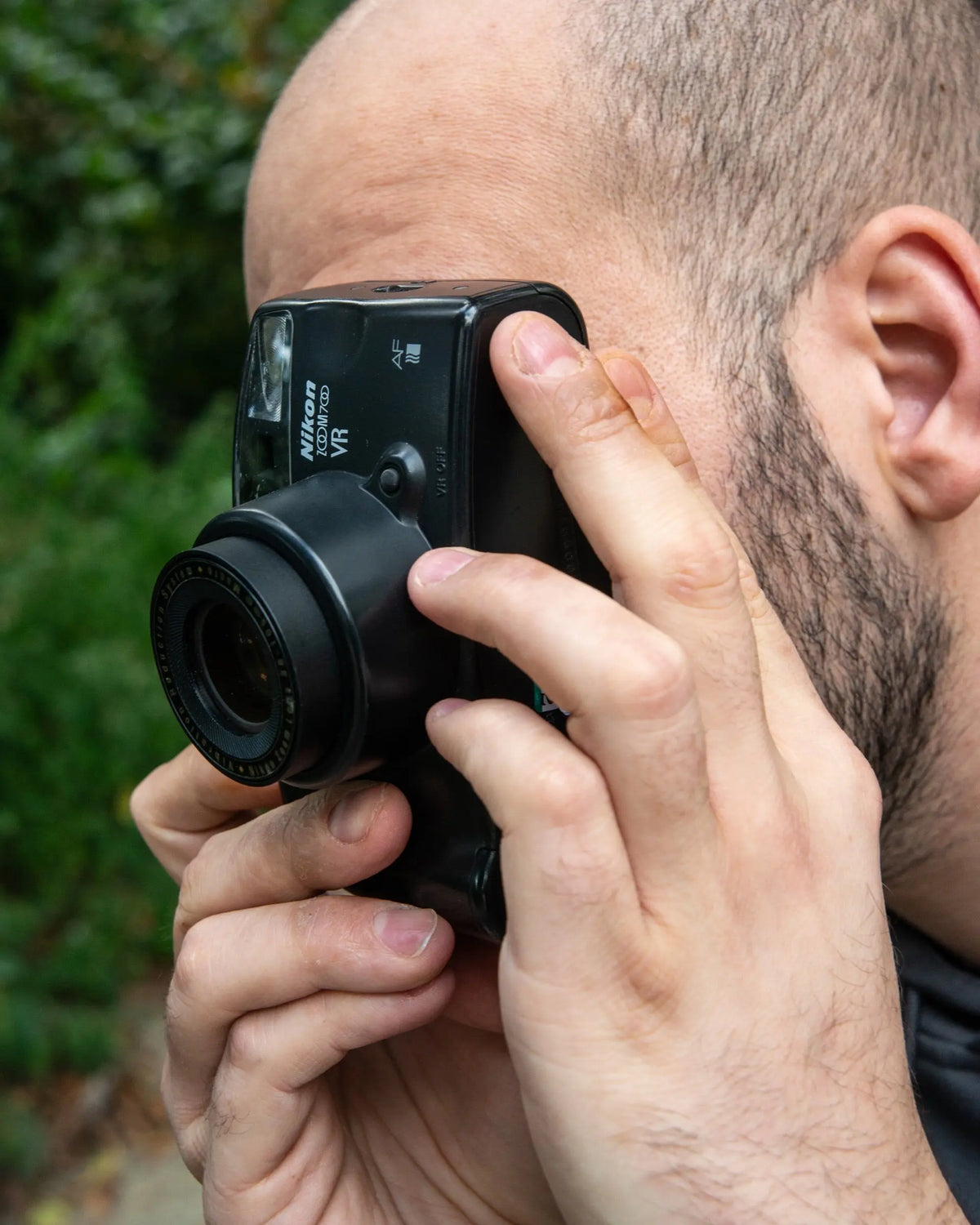 Photographer looking through a compact film camera