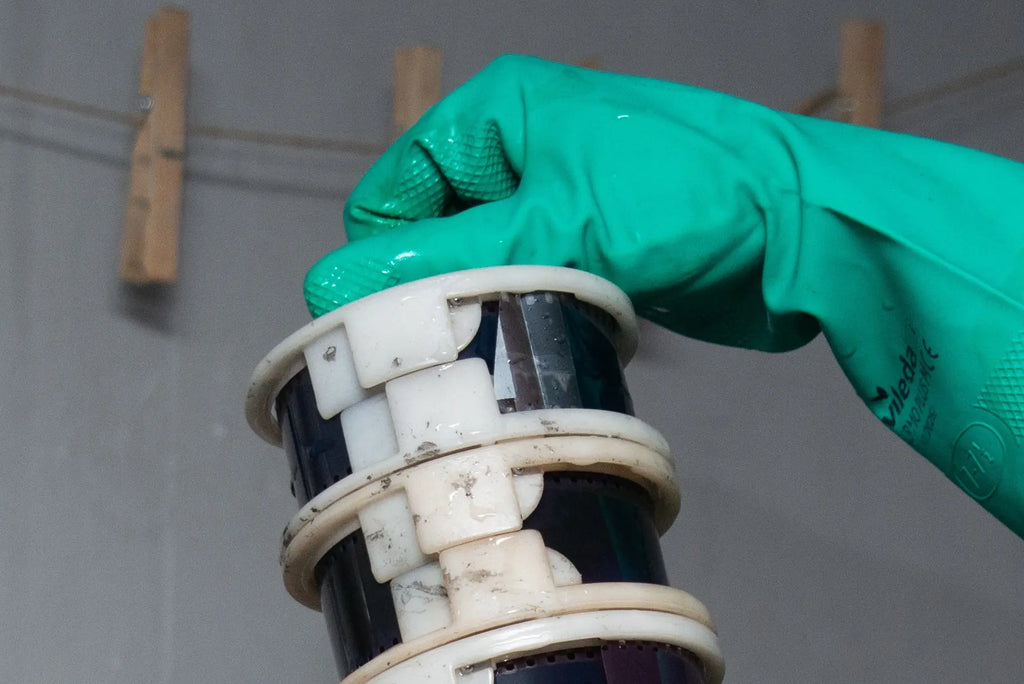 Gloved hand lifting stacked film reels from a tank at Berlin Photo Studio