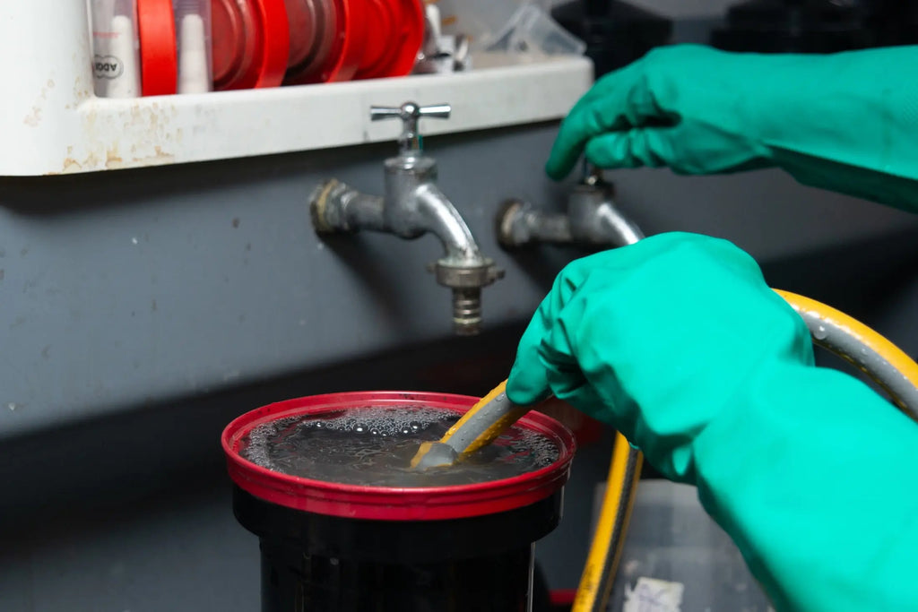 Technician rinsing a development tank with a hose at Berlin Photo Studio